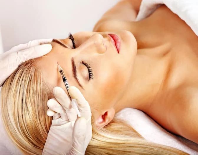Provider placing an injectable along a reclined client's cheek
