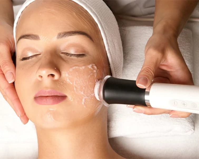 OxyGeneo handpiece on a client's cheek, oxygen bubbles rising on the skin