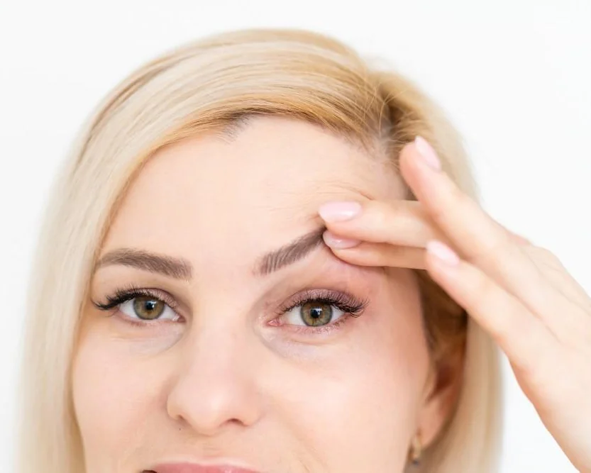 Woman lifting the skin at her upper eyelid