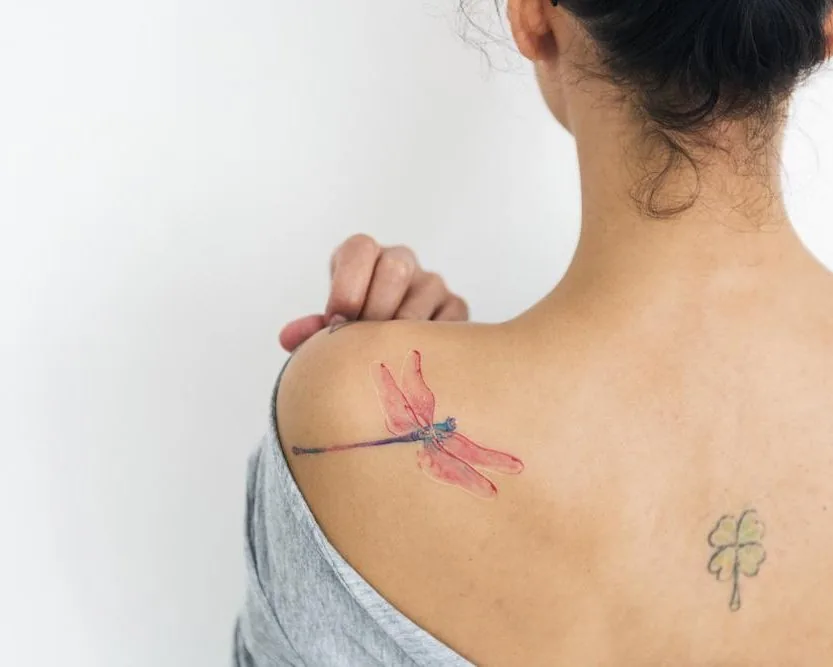 Red and blue dragonfly tattoo on a shoulder, the kind of colored ink a Pico laser can clear