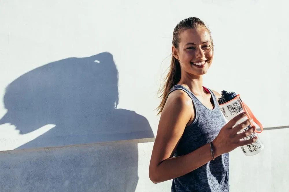Woman in exercise clothing holding a reusable water bottle